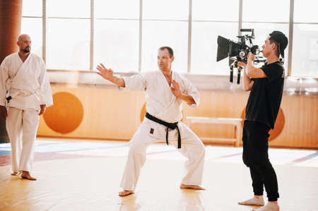 Operator with big camera shoots karate training on tatamiの写真素材