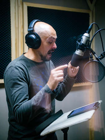 Expressive face of bald man near microphoneの写真素材