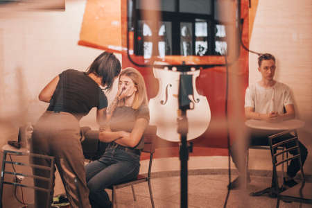 Actors waiting on stage, while pretty Make up artist worksの写真素材