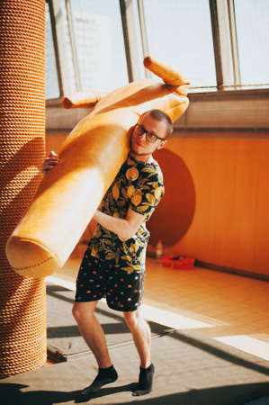 Young Guy in glasses drags a training mannequin.の写真素材