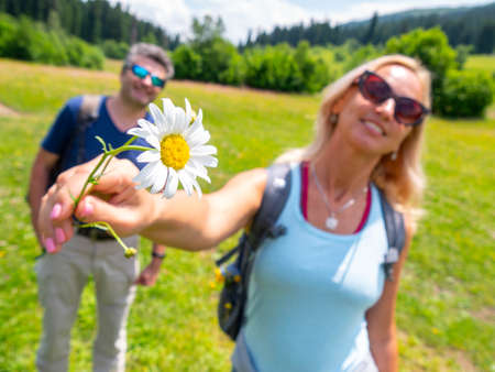 Gentle chamomile in hand if blonde woman on a valley near the husbandの写真素材