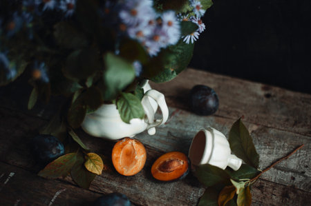 Cut plum near the old fashioned clay vase on wooden tableの写真素材