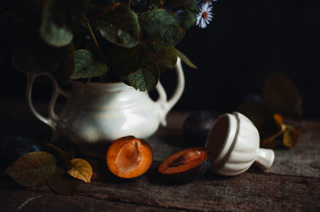 Cozy autumn village scene. Ripe plum near clay vaseの写真素材