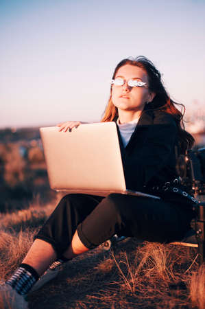 Cool modern girl with laptop on skateboardの写真素材