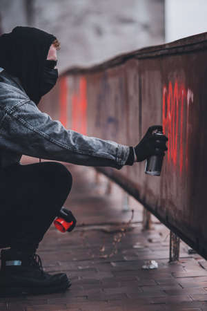 Using spray paint can to make protest sign. Charismatic man with hidden identityの写真素材
