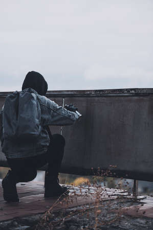 Military styled man starts to paint something on the wall with spray paintの写真素材