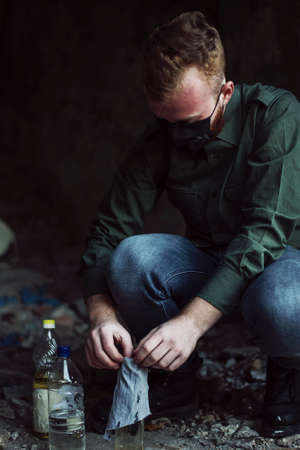 Protester in black mask makes molotovs cocktail in abandoned buildingの写真素材