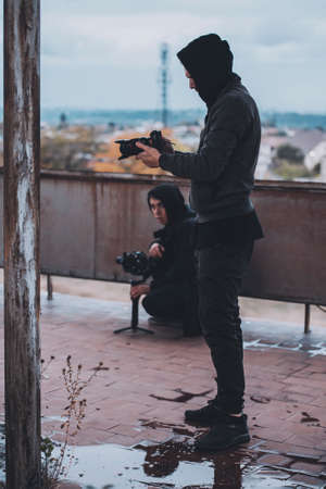 Young operator in hood shoots on camera with Stab on the roof of abandoned houseの写真素材