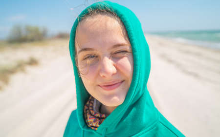 Sweet teenage girl in hood smiling portrait on the beach.の写真素材