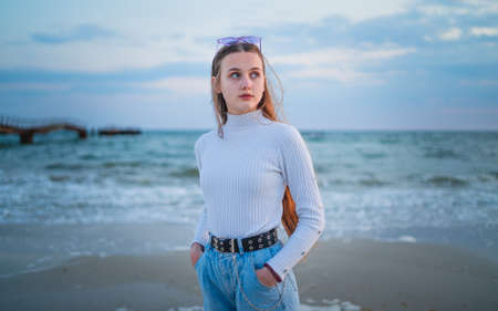 Gentle shy girl looks on the sunset near the seaの写真素材