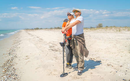 Adult couple with metal detectors on the wild sea coastの写真素材