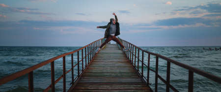 Crazy jump of young man at pier in the seaの写真素材