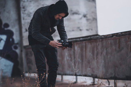 Young cameramen works on the roof of abandoned building. Shooting with a hands. Operator work...