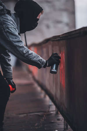 Close shoot of Young anonymous graffitist making protest graffiti with red spray paintの写真素材