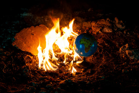 Close up of globe in fire at the floor of abandoned building. Allusion to a world of nowadays.の写真素材
