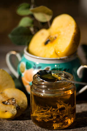 Autumn still life photo of ripe quince in grandmas vase near the honey cupの写真素材