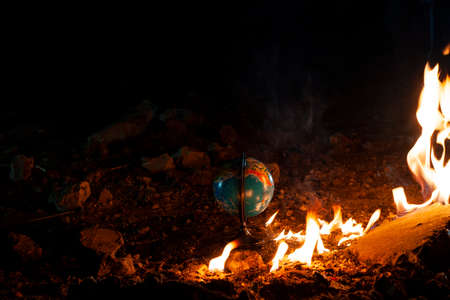Globe stay on the rocky floor near the flaming fire. Light of fire illuminates an Earthの写真素材