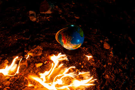 Close up of globe in fire at the floor of abandoned building. Allusion to a world of nowadays.の写真素材