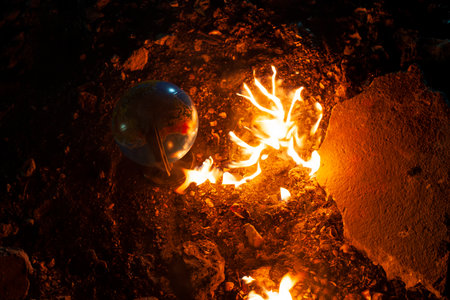 Globe stay on the rocky floor near the flaming fire. Light of fire illuminates an Earthの写真素材
