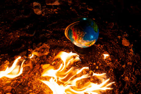 Close up of globe in fire at the floor of abandoned building. Allusion to a world of nowadays.の写真素材