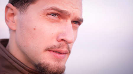 Macho attractive appearance handsome bearded troubled about something portrait. His blue eyes looking upset in sunset lightの写真素材