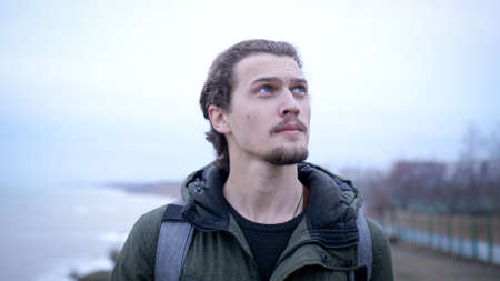 Portrait of young depressed male lonely walks on a winter beach break.の写真素材