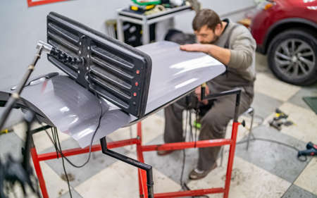 Bearded mans car repair service worker, hands photo in work repair process with a car doorの写真素材