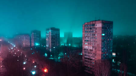 Neon lighted urban aerial panorama in a bad ghetto district. Deep blue colored light just from the dark on the horizonの写真素材
