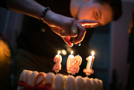 The man lights candles on the cake and preparing for the holidayの写真素材