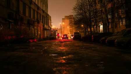 A dark street with light at the end in the city at the nightの写真素材