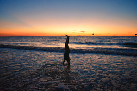 Clearwater, Florida. October 21,2018 Girl doing handstand over blue sea on colorful sunset at Clearwater Beachのeditorial素材