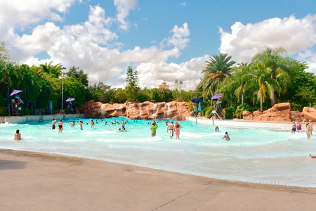 Orlando, Florida. October 26, 2018. People enjoying pool with falls on green forest background and cloudy blue sky at Aquatica Water Park.のeditorial素材