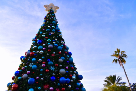 Orlando, Florida; November 24, 2018. Beautiful decorated Christmas Tree and Palms Trees on cloudy lightblue sky background in International Drive area.のeditorial素材