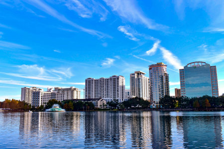 Orlando, Florida . December 24, 2018. Panoramic view of downtown buildings, vintage fountain and swan boat on lightblue cloudy background in Lake Eola Park area.のeditorial素材