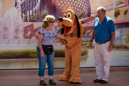 Orlando, Florida . March 27, 2019. Pluto taking the hands of a senior woman at Epcot in Walt Disney...