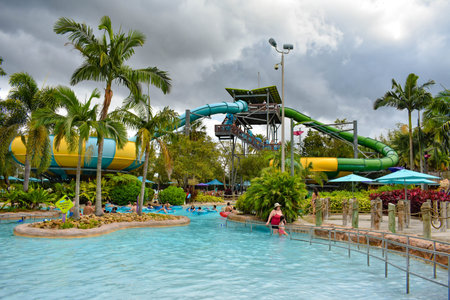 Orlando, Florida. April 07, 2019. Water attraction, palm trees and pool on cloudy sky background at Aquatica water park.のeditorial素材