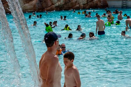 Orlando, Florida. April 07, 2019. Man under the waterfall and panoramic view of people enjoying the pool at Aquatica water park.のeditorial素材
