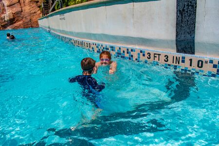 Orlando, Florida. May 20, 2019. Brother and sister splashing in pool at Aquatica in International Drive area (2)のeditorial素材
