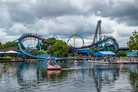 Orlando, Florida. June 17, 2019. Couple enjoying Swan paddle boat and panoramic view of Mako and Kraken rollercoaster at Seaworld.のeditorial素材