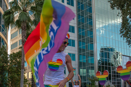 Orlando, Florida. October 12, 2019. Rainbow flag and Disney Gay community man in Come Out With Pride Orlando parade at Lake Eola Park area 89のeditorial素材