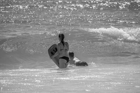 Daytona Beach Florida. July 07, 2019 Girl and boy with surfboard enjoying waves at Main Street Pier area.のeditorial素材
