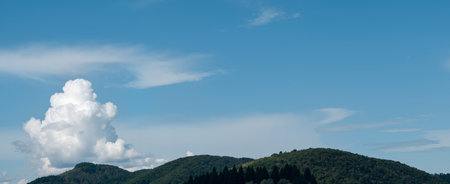 Panoramic view of green hills and blue sky with white cloudsの素材