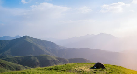 Camping in the mountains. Panoramic view of a green meadow with a tent.の素材