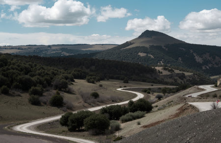 Mountain road in the mountains under the blue sky with white cloudsの素材