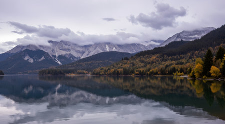 Autumn view of lake with reflection of mountains and clouds in waterの素材