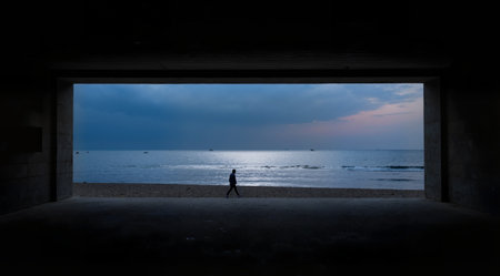 Silhouette of a man walking in a tunnel on the beachの素材