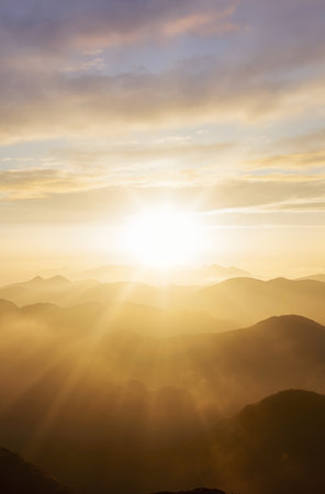 Sunrise in the mountains with fog and sunbeams on the horizonの素材
