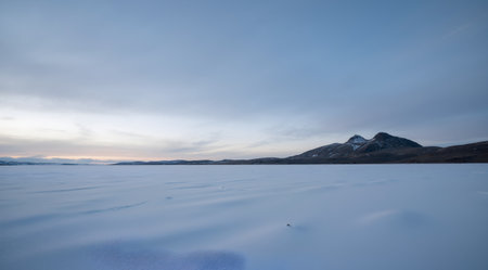 Beautiful winter landscape with frozen lake and mountains in the background.の素材