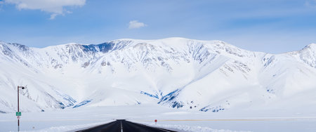 Highway in the snowy mountains on a background of blue sky.の素材