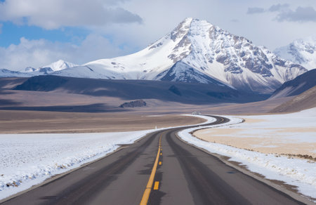 Road in the desert with snow-capped mountains in the backgroundの素材